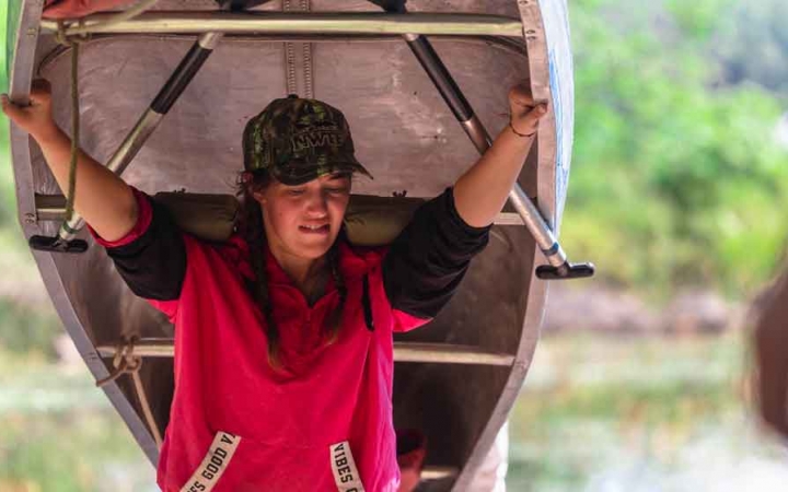 a student portages a canoe on an outward bound gap year expedition 